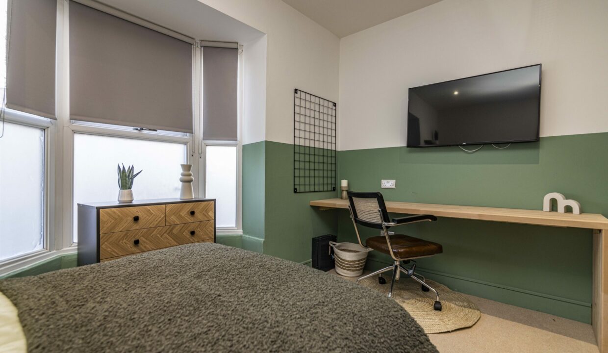 Student bedroom with green accent wall and study space